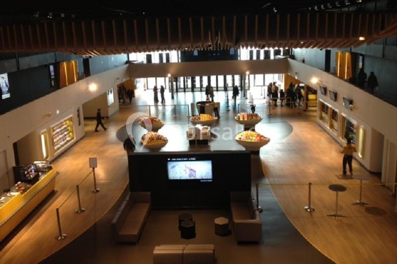 Vue intérieure d'un hall spacieux avec des comptoirs, des sièges et des visiteurs en arrière-plan.