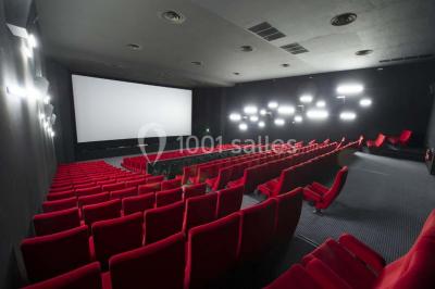 Salle vide avec moquette sombre, grande baie vitrée et structures métalliques visibles en arrière-plan.