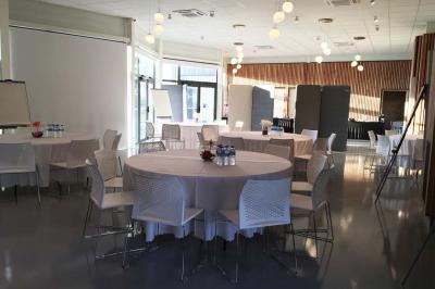 Salle de réception décorée avec des tables rondes, nappes blanches, serviettes orange et centres de table floraux.