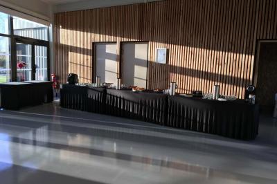 Salle de réception décorée avec des tables rondes, nappes blanches, serviettes orange et centres de table floraux.