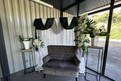 Salle de réception décorée avec des tables rondes, nappes blanches, serviettes orange et centres de table floraux.