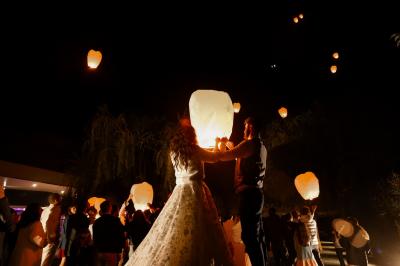 Salle de réception décorée avec des tables rondes, nappes blanches, serviettes orange et centres de table floraux.