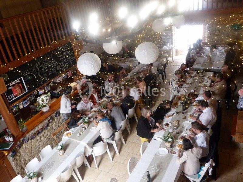 Salle décorée avec des guirlandes lumineuses, accueillant des convives attablés pour un repas collectif.