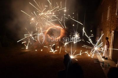 Personne manipulant un objet enflammé, créant des étincelles circulaires dans un environnement sombre.