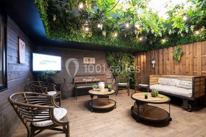 Espace intérieur aménagé avec des meubles en bois, des plantes suspendues et un éclairage chaleureux.
