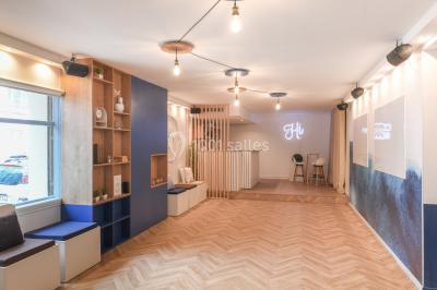 Salle lumineuse avec parquet en chevrons, murs décorés de bleu et blanc, et mobilier moderne en bois clair.