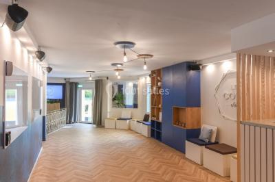 Salle lumineuse avec parquet en chevrons, murs décorés de bleu et blanc, et mobilier moderne en bois clair.