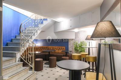 Salle lumineuse avec parquet en chevrons, murs décorés de bleu et blanc, et mobilier moderne en bois clair.