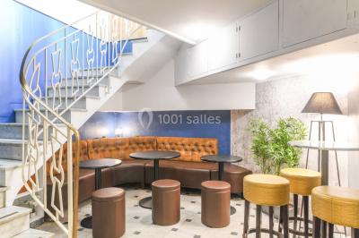 Salle lumineuse avec parquet en chevrons, murs décorés de bleu et blanc, et mobilier moderne en bois clair.