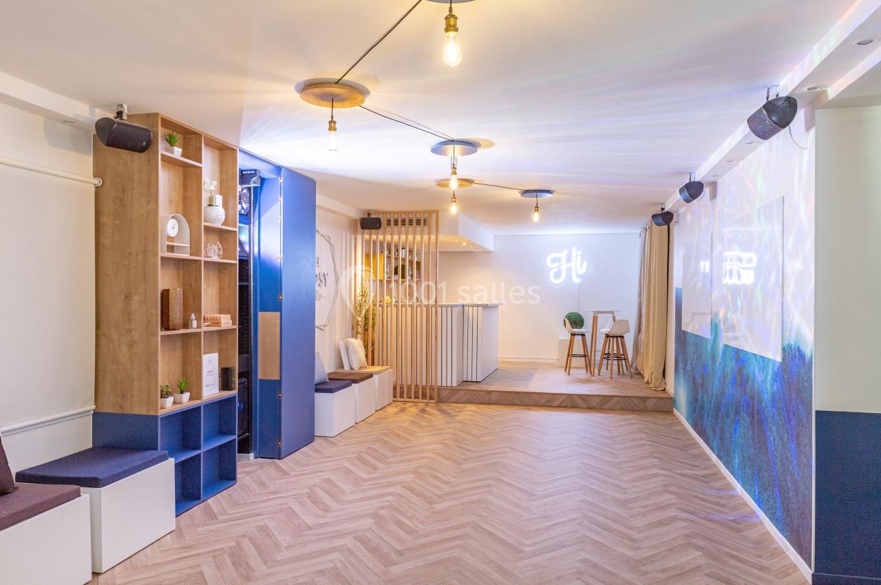 Salle lumineuse avec parquet, espace bar, étagères en bois, banquettes et décorations modernes.