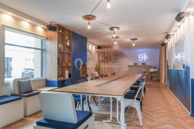 Salle lumineuse avec parquet en chevrons, murs décorés de bleu et blanc, et mobilier moderne en bois clair.