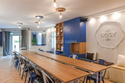 Salle lumineuse avec parquet en chevrons, murs décorés de bleu et blanc, et mobilier moderne en bois clair.