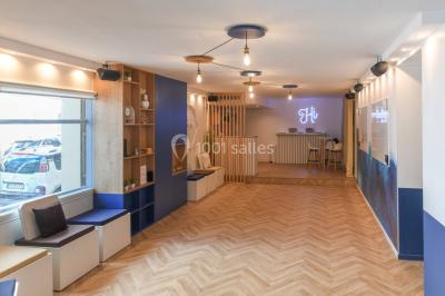 Salle lumineuse avec parquet en chevrons, murs décorés de bleu et blanc, et mobilier moderne en bois clair.