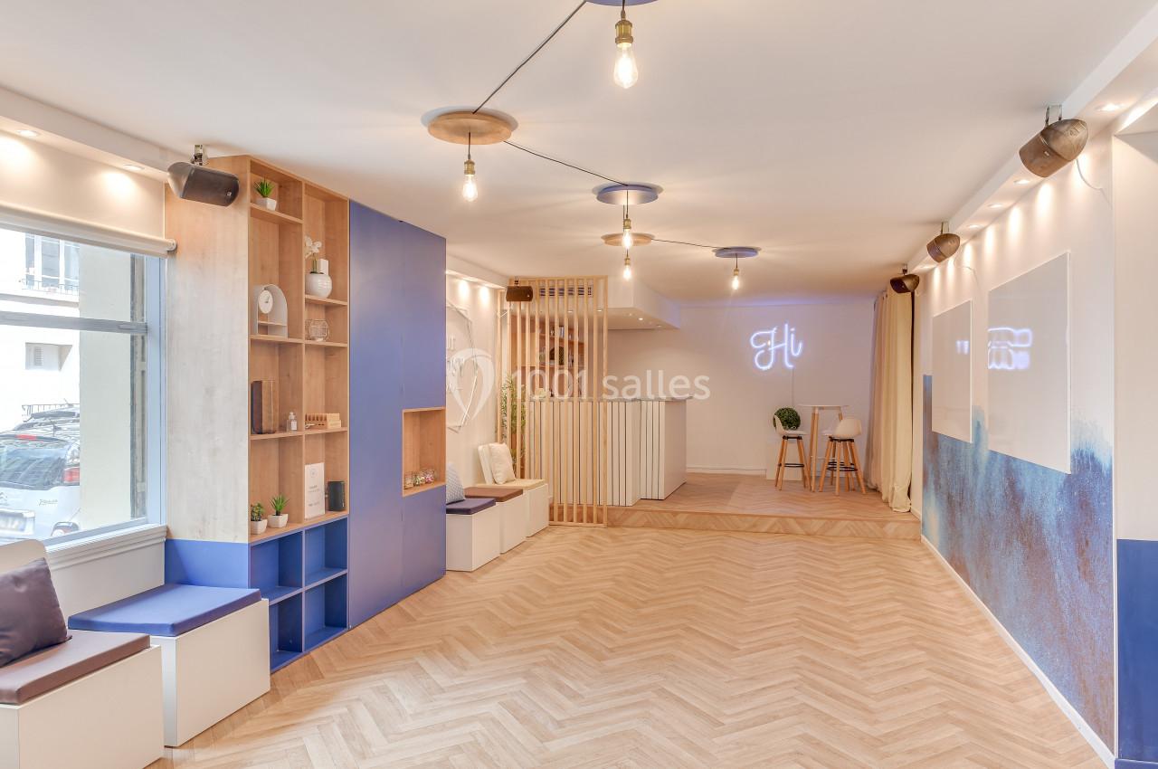 Salle lumineuse avec parquet en chevrons, murs décorés de bleu et blanc, et mobilier moderne en bois clair.
