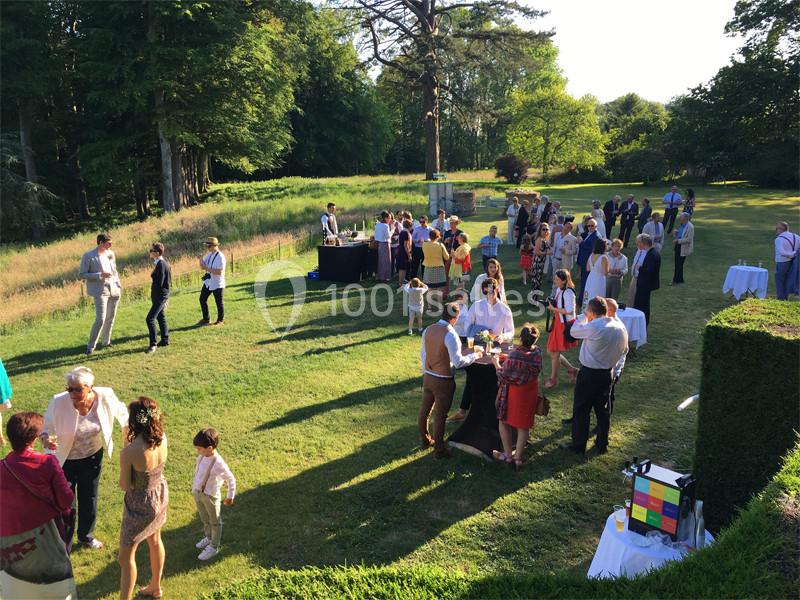 Groupe de personnes réunies en plein air dans un jardin, discutant et partageant un moment convivial sous un ciel dégagé.