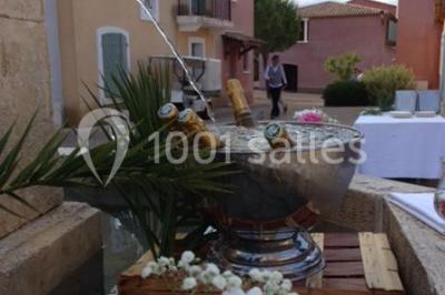 Gâteau de mariage à quatre étages décoré de rubans beige clair, posé sur un présentoir blanc.