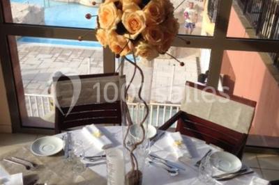 Gâteau de mariage à quatre étages décoré de rubans beige clair, posé sur un présentoir blanc.