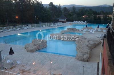 Gâteau de mariage à quatre étages décoré de rubans beige clair, posé sur un présentoir blanc.