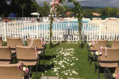 Gâteau de mariage à quatre étages décoré de rubans beige clair, posé sur un présentoir blanc.