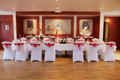 Gâteau de mariage à quatre étages décoré de rubans beige clair, posé sur un présentoir blanc.
