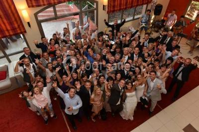 Gâteau de mariage à quatre étages décoré de rubans beige clair, posé sur un présentoir blanc.