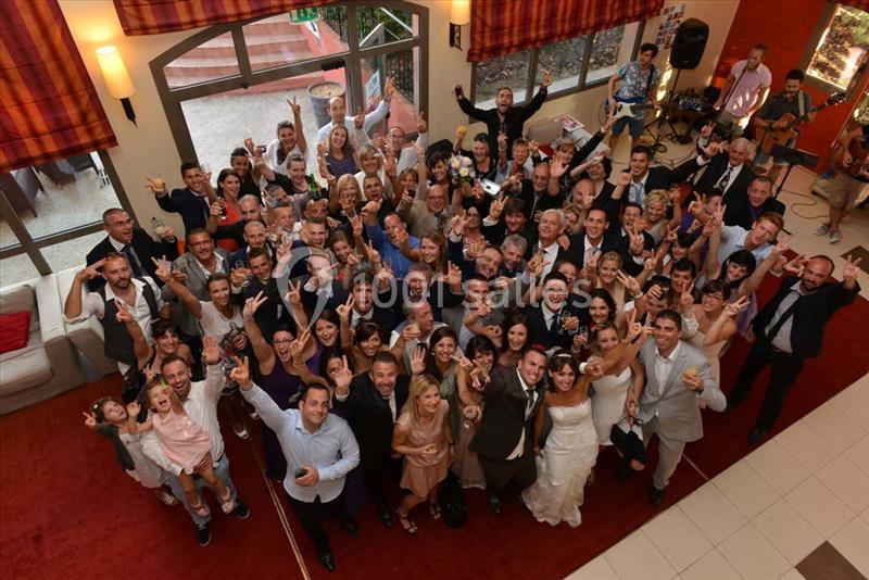 Groupe de personnes souriantes rassemblées dans une salle, certaines levant les bras, lors d'un événement festif.