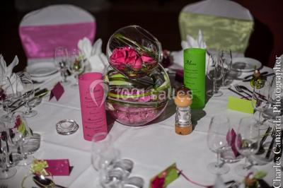 Gâteau de mariage à quatre étages décoré de rubans beige clair, posé sur un présentoir blanc.