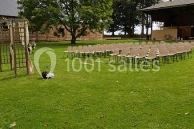 Paysage champêtre avec pelouse verdoyante, arbres en arrière-plan et buissons fleuris sous un ciel bleu dégagé.
