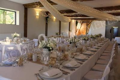 Paysage champêtre avec pelouse verdoyante, arbres en arrière-plan et buissons fleuris sous un ciel bleu dégagé.