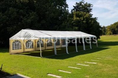 Paysage champêtre avec pelouse verdoyante, arbres en arrière-plan et buissons fleuris sous un ciel bleu dégagé.