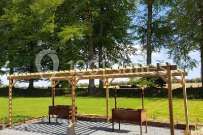 Paysage champêtre avec pelouse verdoyante, arbres en arrière-plan et buissons fleuris sous un ciel bleu dégagé.
