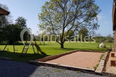 Paysage champêtre avec pelouse verdoyante, arbres en arrière-plan et buissons fleuris sous un ciel bleu dégagé.