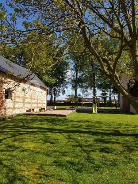 Cour herbeuse avec un bâtiment en briques, des arbres ombrageant le terrain et un ciel dégagé en arrière-plan.
