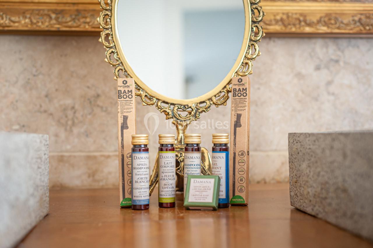 Produits de soins et brosses à dents en bambou disposés devant un miroir doré sur une surface en bois.