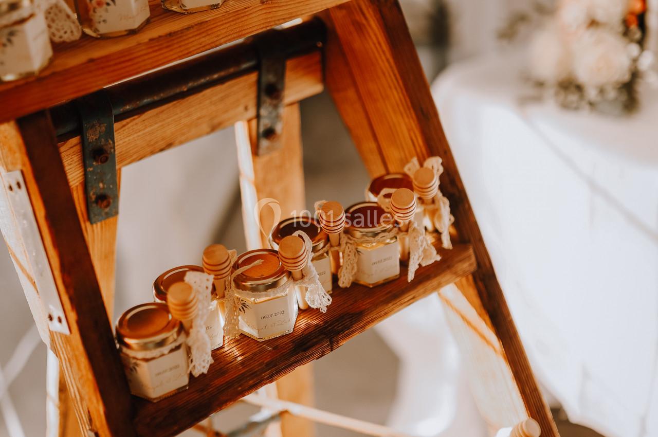 Petits pots de miel disposés sur une échelle en bois, décorée pour un événement festif ou un mariage.