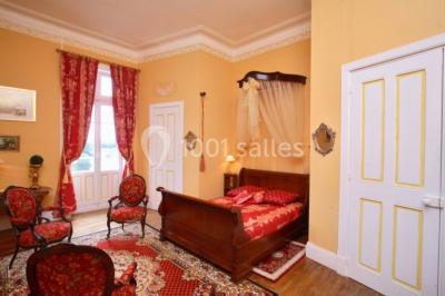 Salle de bain avec baignoire sur pieds, douche vitrée, lavabo, toilettes et carrelage beige décoré de motifs floraux.