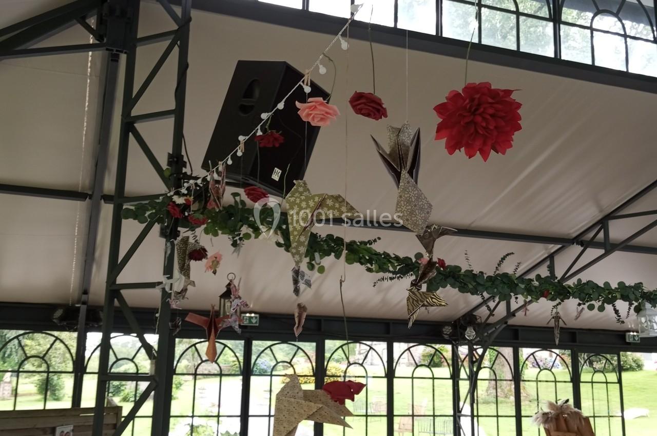 Décorations suspendues en papier et tissu, représentant des oiseaux et des fleurs, dans une salle lumineuse avec verrières.