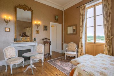 Salle de bain avec baignoire sur pieds, douche vitrée, lavabo, toilettes et carrelage beige décoré de motifs floraux.