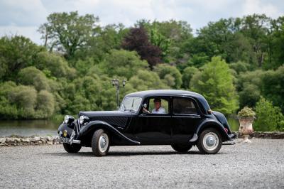 Salle de bain avec baignoire sur pieds, douche vitrée, lavabo, toilettes et carrelage beige décoré de motifs floraux.