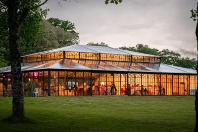 Salle de bain avec baignoire sur pieds, douche vitrée, lavabo, toilettes et carrelage beige décoré de motifs floraux.