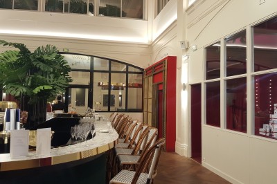 Vue intérieure d'une galerie lumineuse avec verrière, murs blancs et suspensions circulaires rouges.