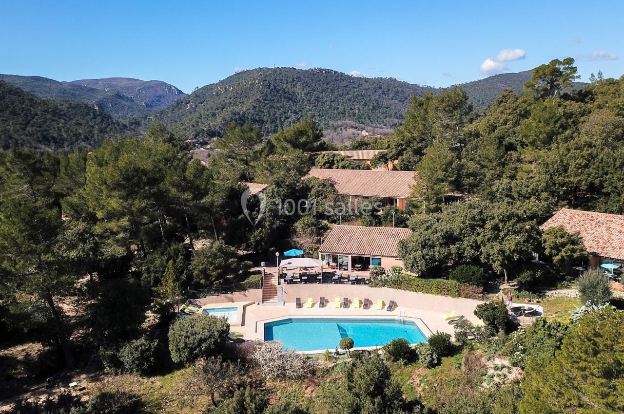 Vue aérienne d'un domaine avec des bâtiments en tuiles entourés de végétation et une piscine au centre.