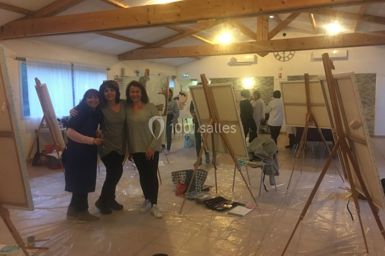 Des personnes posent devant des chevalets dans une salle lumineuse dédiée à une activité artistique.
