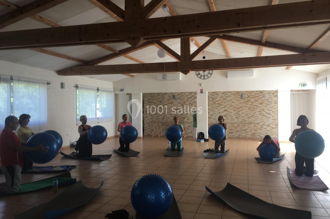 Personnes participant à une séance de fitness avec des ballons de gym dans une salle lumineuse au plafond en bois.