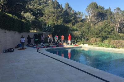 Des personnes allongées sur des transats sous des parasols, profitant du soleil près d'une piscine.