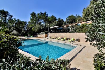 Des personnes allongées sur des transats sous des parasols, profitant du soleil près d'une piscine.