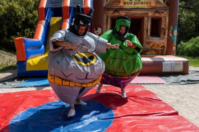 Des personnes allongées sur des transats sous des parasols, profitant du soleil près d'une piscine.