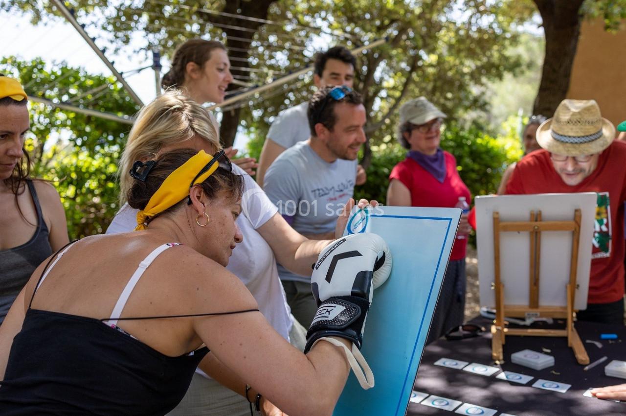 Des personnes participent à une activité de peinture en plein air, dont une femme portant un gant de boxe.