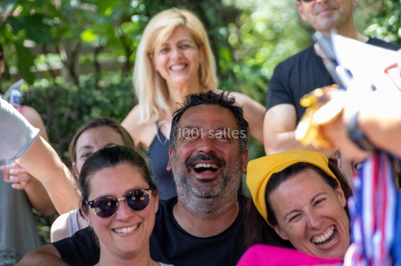 Groupe de personnes souriantes lors d'un rassemblement en extérieur, entourées de verdure.