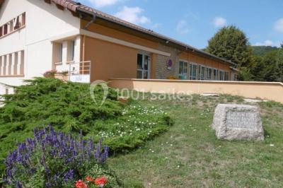 Aire de jeux extérieure avec toboggan, balançoires et structures en bois, entourée de pelouse et d'arbres.